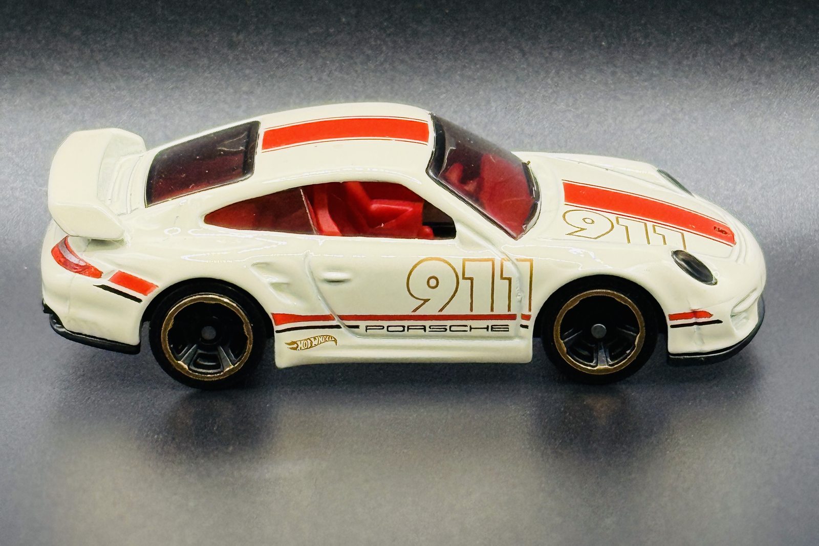 A white Hot Wheels Porsche 911 with gold 911 livery